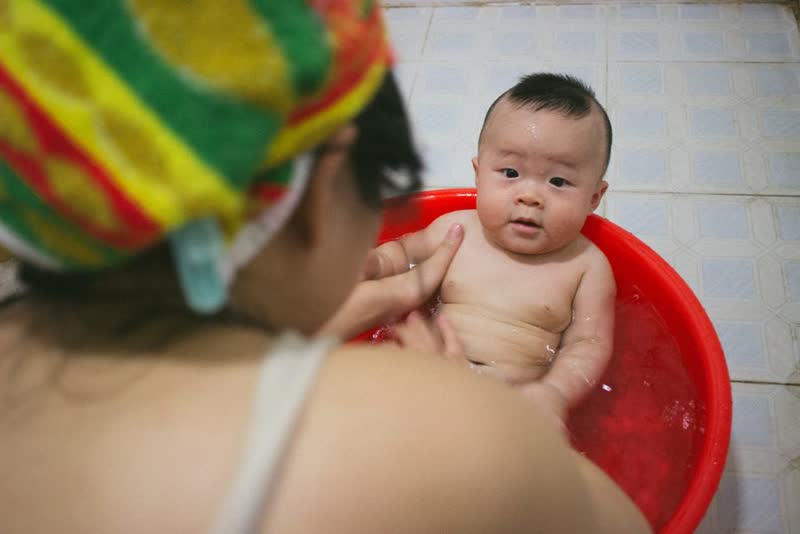 Mẹ Việt tắm cho bé trong chậu đỏ